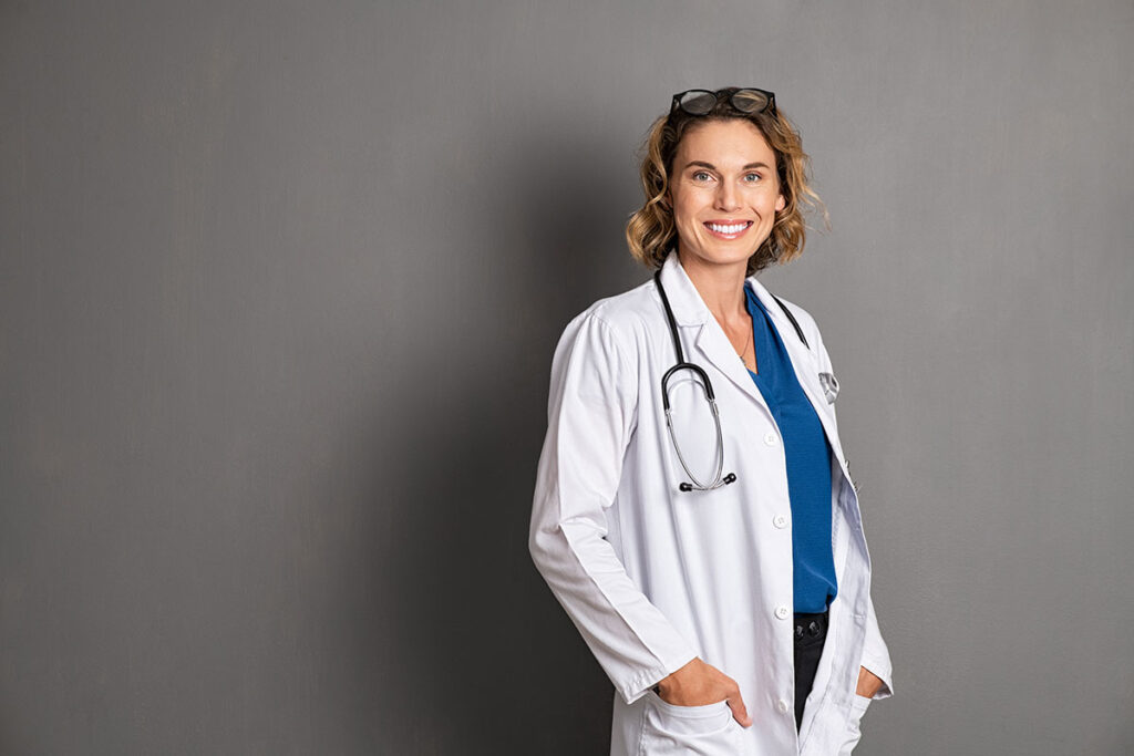 Eine Ärztin steht vor einer grauen Wand